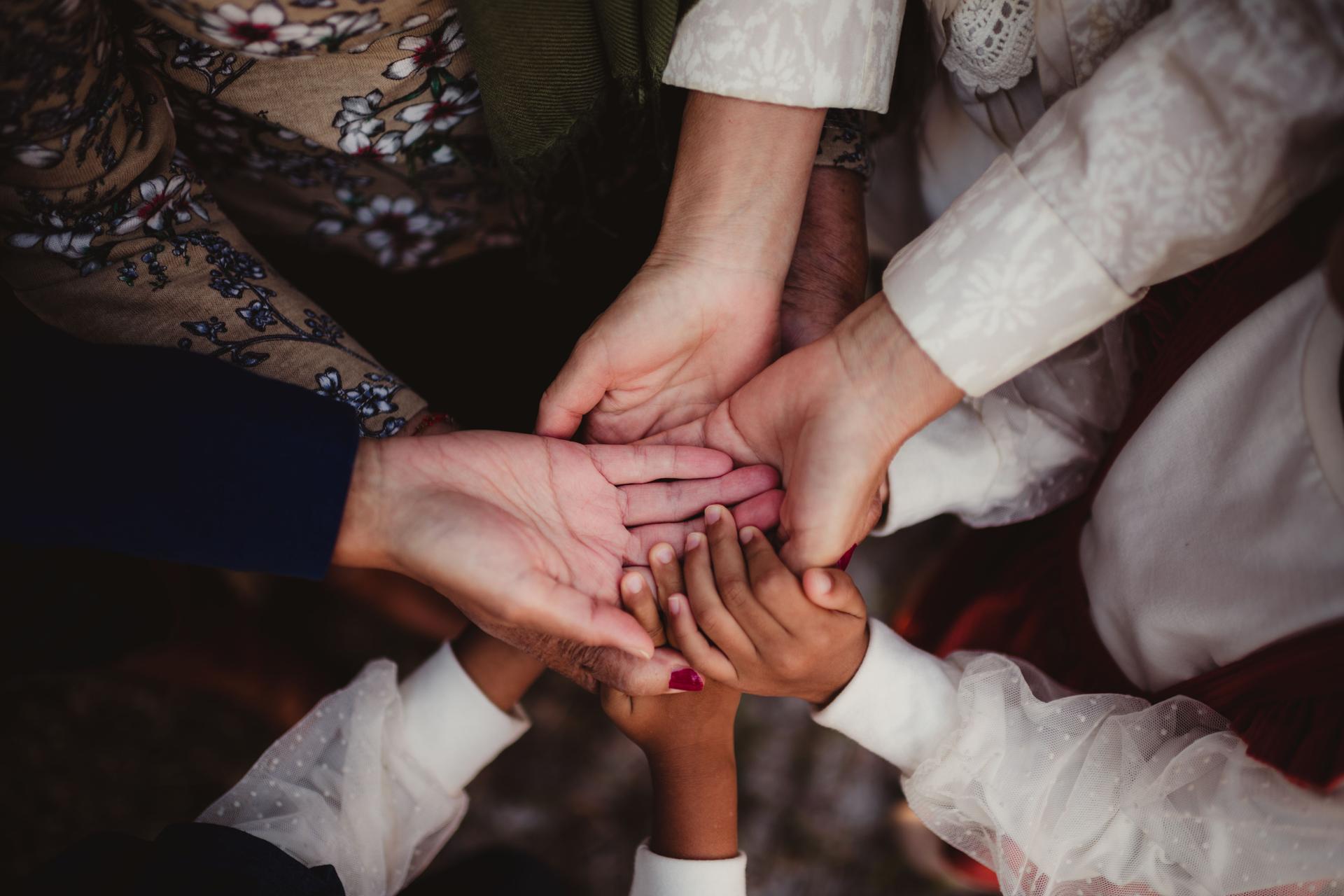 Family of children, parents and grandparents with hands together in center