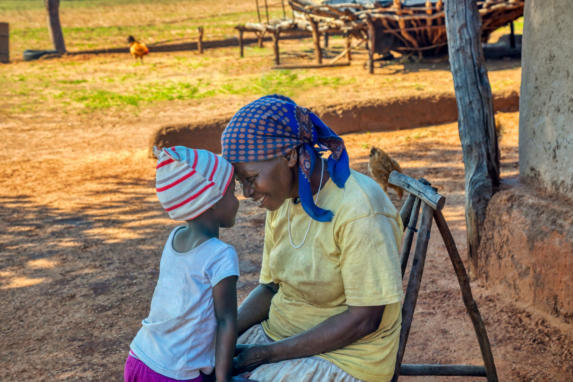 Granny telling a story to her granddaughter in the yard of a village